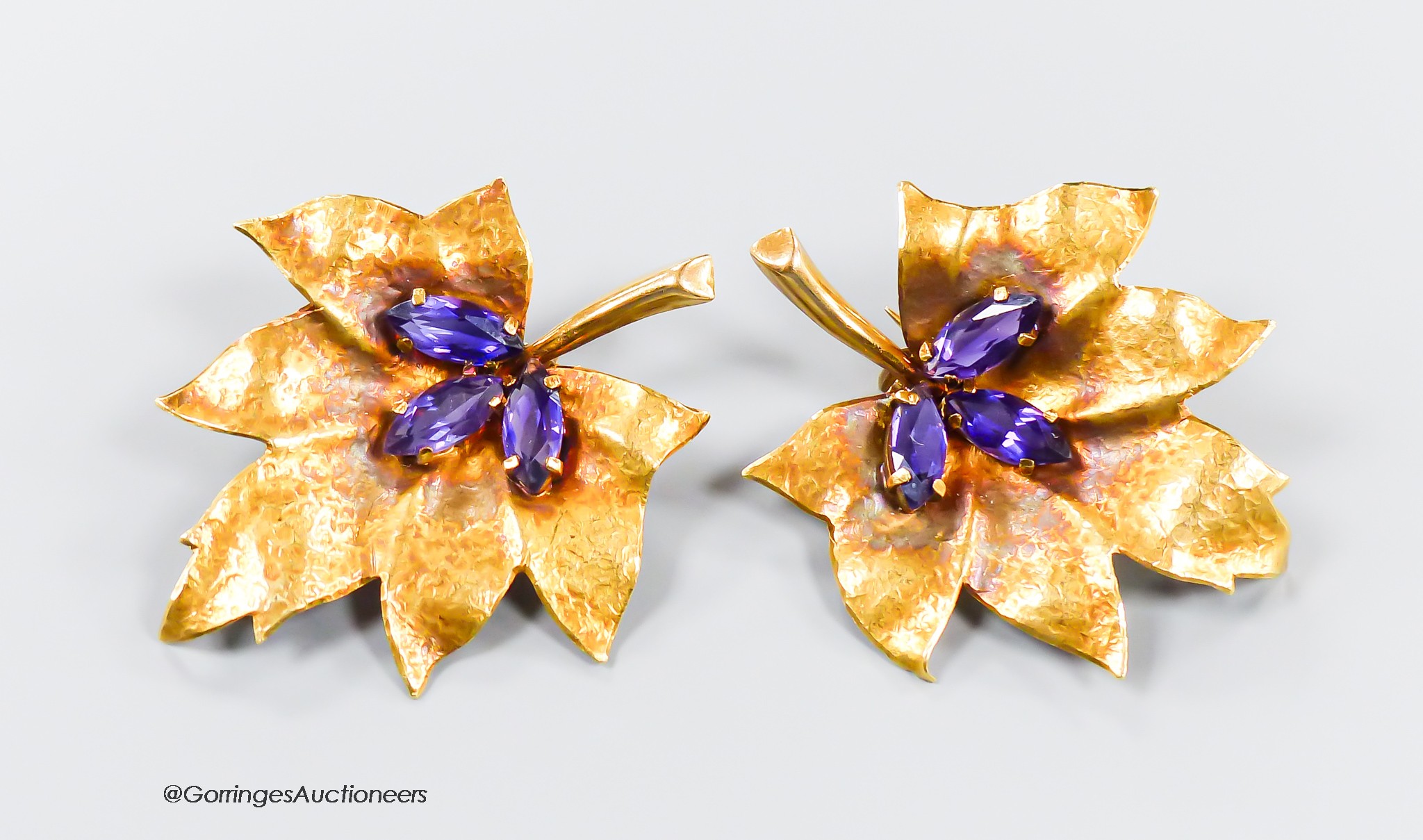 A pair of 750 yellow metal and three stone amethyst set leaf brooches, 38mm, gross 11.2 grams.